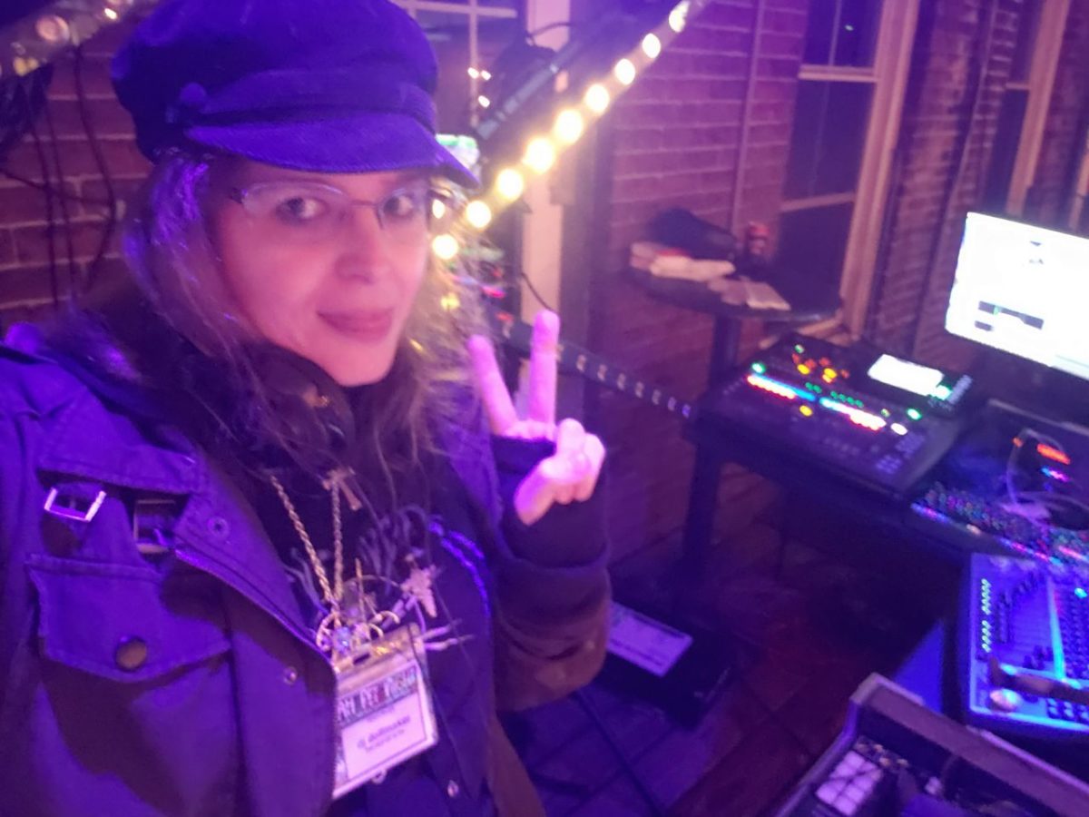 dj dollmaker flashing a peace sign in front of DJ equipment in front of a brick building facade at night, with lights shining at 168 York Street Cafe, October 2022